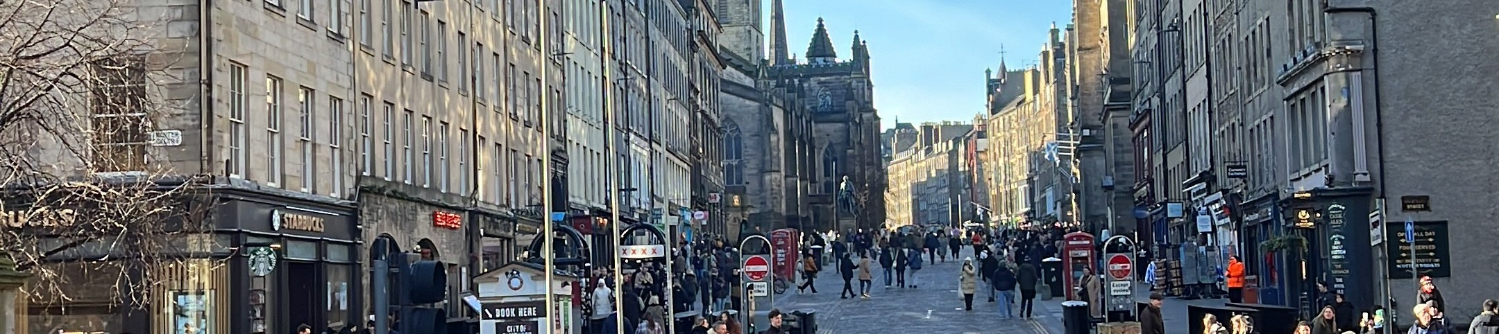 Vista panorámica de Royal Mile en Edinburgh, con el pavimento de piedra y las fachadas históricas a ambos lados